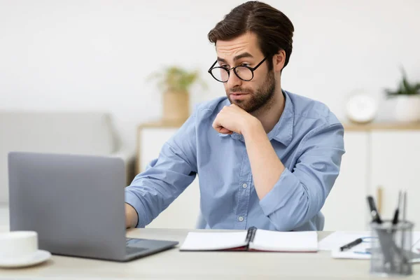 Surpirado cara de negócios olhando para laptop sentado no escritório — Fotografia de Stock