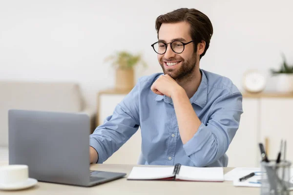 Χαμογελώντας επιχειρηματίας που εργάζεται σε φορητό υπολογιστή κάθεται στο γραφείο στο γραφείο — Φωτογραφία Αρχείου