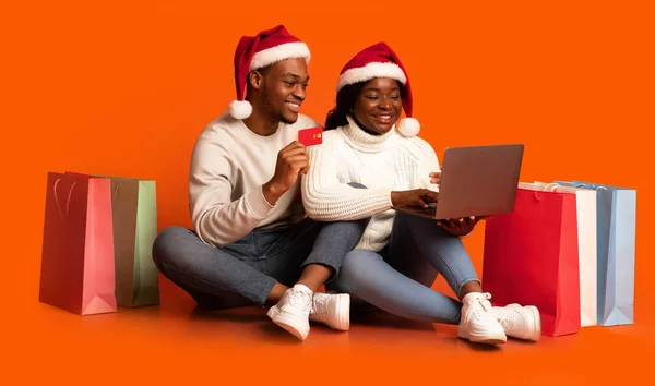 Julshopping. Svart par köpa presenter på nätet, med hjälp av laptop och kreditkort — Stockfoto