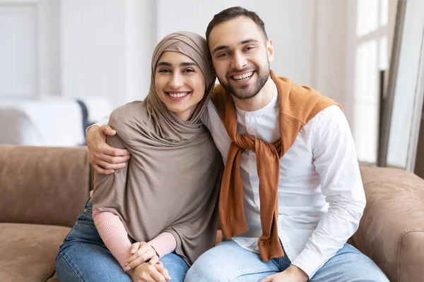 Boldog muszlim pár ölelkező ül együtt kanapén otthon — Stock Fotó