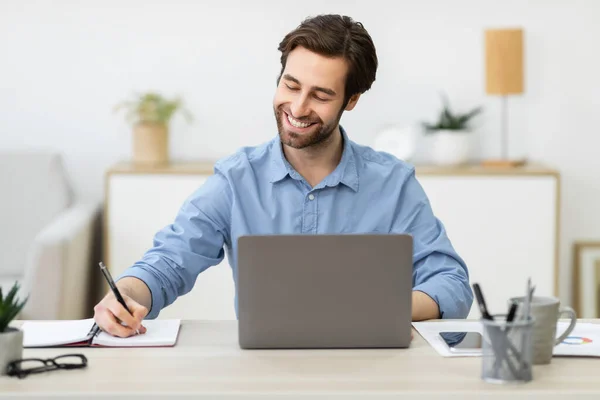 Vrolijke zakenman aan het werk op Laptop neemt notities zittend op het werk — Stockfoto