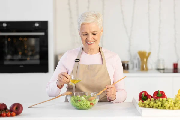 Reife Frau kocht Salat zum Abendessen in der Küche zu Hause — Stockfoto