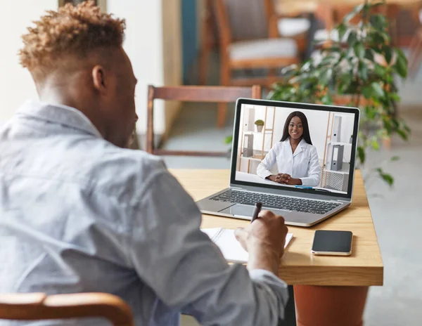 Appointment with doctor online. Black guy having video chat with therapist, receiving professional medical help remotely