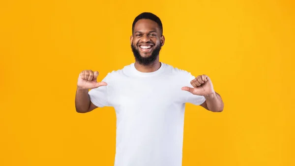 Gelukkig Afrikaans man wijzend duimen naar zichzelf over gele achtergrond — Stockfoto