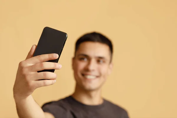 Smartphone en la mano de sonriente millennial chico blogger estudiante, haciendo foto — Foto de Stock