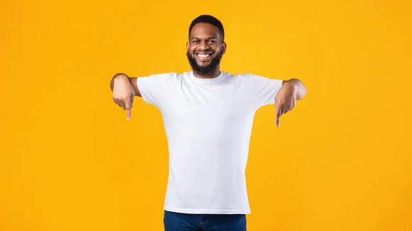 African Guy zeigt mit den Fingern nach unten Werbung etwas über gelbem Hintergrund — Stockfoto