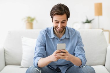 Heyecanlı Adam Evdeki Kanepede Otururken Telefon Mesajı Kullanıyor