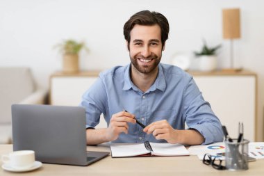 İş yerinde dizüstü bilgisayarın başında otururken mutlu iş adamı pozu