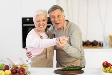 Olgun eşler yemek pişiriyor ve mutfakta eğleniyor.