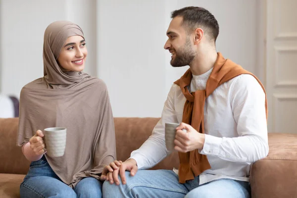 Giovane coppia musulmana che parla e flirta bevendo caffè a casa — Foto Stock