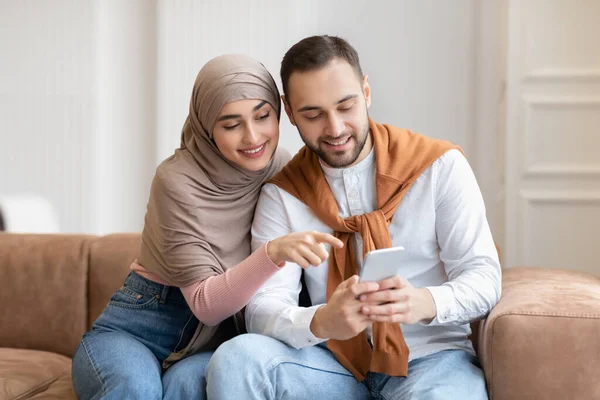 Muslimisches Paar mit Handy auf Sofa zu Hause — Stockfoto