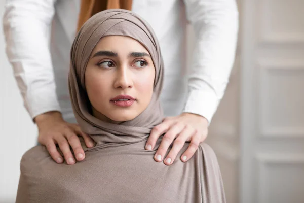 Домашнее насилие, Мусульманский муж трогает плечи напуганной жены в помещении — стоковое фото
