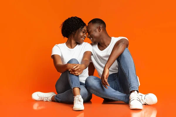 Känslomässiga svarta älskare kramas på orange bakgrund — Stockfoto