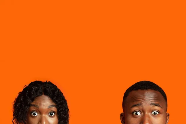 stock image Shocked black couple with big eyes hiding from someone