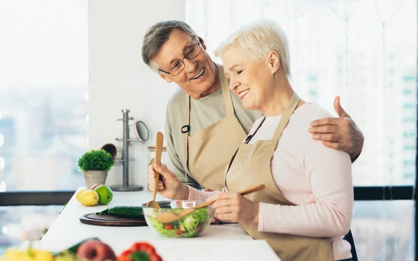 Pohled z boku Happy Senior manželé vaření v moderní kuchyni — Stock fotografie