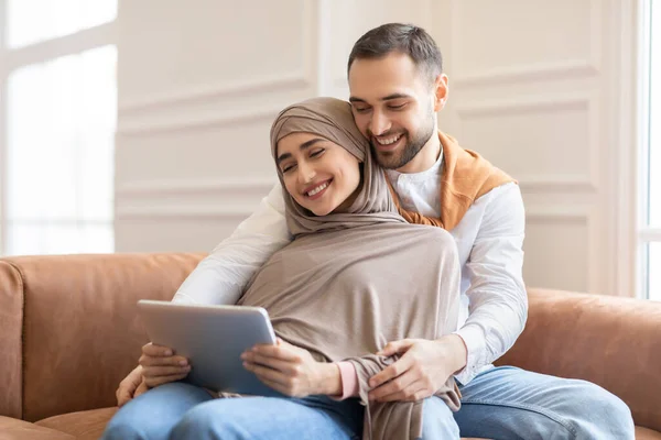 Μουσουλμανικό ζευγάρι που χρησιμοποιεί tablet βλέποντας ταινία σε απευθείας σύνδεση συνεδρίαση στο σπίτι — Φωτογραφία Αρχείου