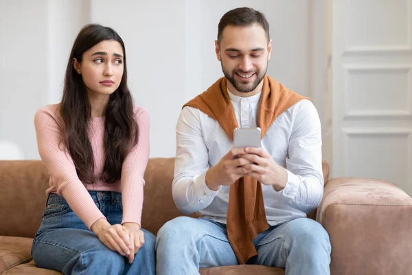 Sad Arab Дружина Дивлячись На Чоловік В той час як Він Texting Indorors — стокове фото