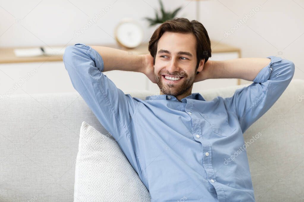 Successful Millennial Guy Resting On Sofa Enjoying Homey Weekend Indoor