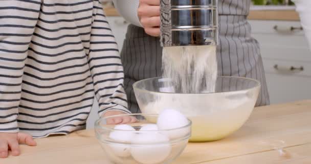 Närbild skott av att lägga mjöl till deg, mor och lille son matlagning tillsammans i köket, slow motion — Stockvideo