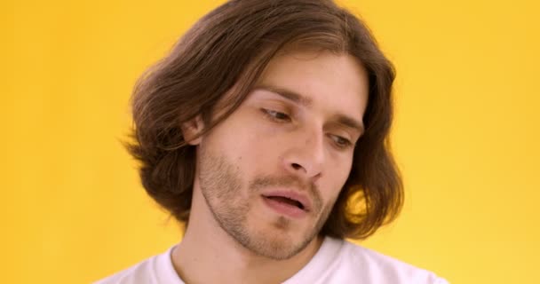 Close up portrait of young doubtful man thinking around, looking at camera with question, yellow background — Stock Video