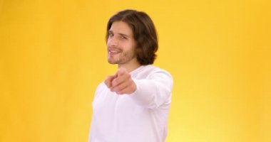 Kendine güveni tam genç adam kamerayı işaret edip göz kırpıyor, seni seçiyor, turuncu stüdyo geçmişi var.