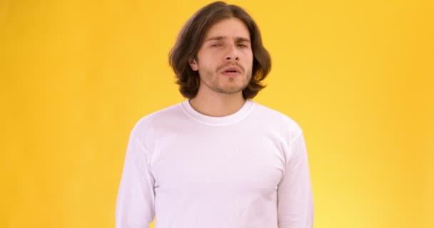 Young man smelling awful scent, covering his nose and frowning face, slow motion, orange studio background — Stock Video