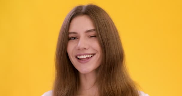 Leuke speelse vrouw knipogen naar camera, flirten met u, gele studio achtergrond — Stockvideo