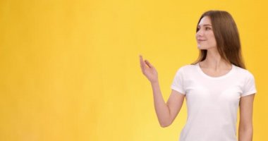 Genç, neşeli bayan elini yana uzatıyor, reklam veriyor, model için boş alan, turuncu arka plan.