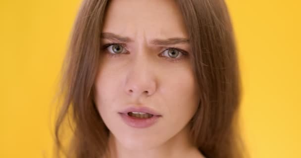Close-up portret van jong verbaasd dame schudden hoofd nee en kijken naar camera met vraag, oranje studio achtergrond — Stockvideo