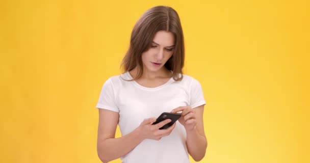 Ung kvinde browsing sociale medier, ser på forfærdelige nyheder og ryster på hovedet i chok, orange studie baggrund – Stock-video