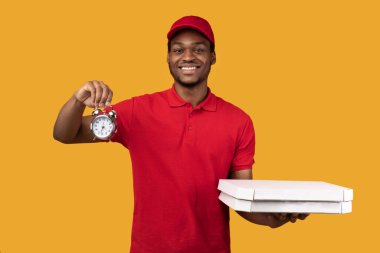 Siyah teslimatçı elinde pizza kutusu ve saat tutuyor.