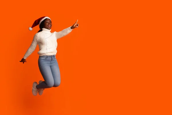 Oferta de Navidad. Joyful Black Santa Lady saltando y señalando el espacio de copia — Foto de Stock