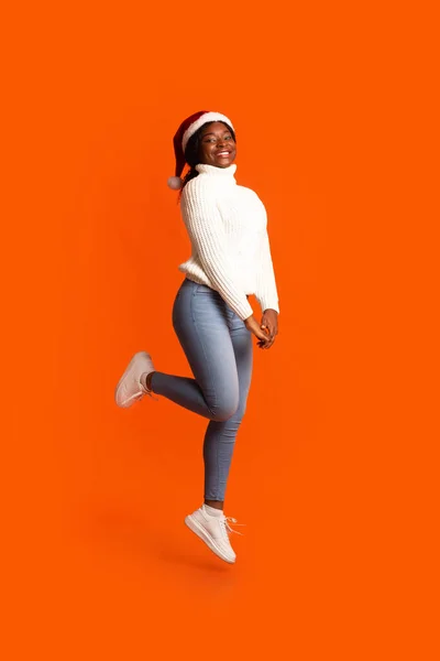 Positive Black Woman In Santa Hat Jumping In Air Over Orange Background — Stock Photo, Image