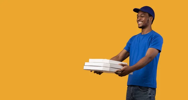 Un repartidor negro sosteniendo cajas de pizza, dándosela al espacio de copia — Foto de Stock