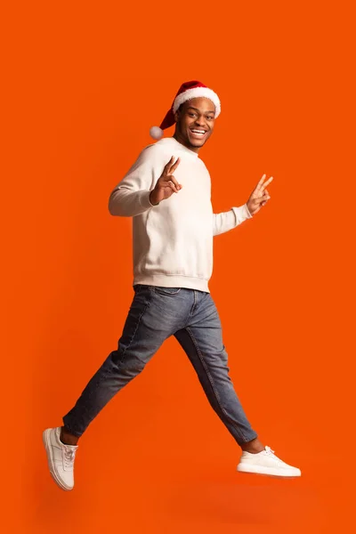 Feestelijke Vreugde. Afrikaanse man in Santa Hat hebben plezier over oranje achtergrond — Stockfoto