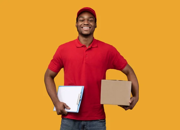 Repartidor afroamericano sujetando portapapeles y caja — Foto de Stock