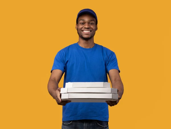 Repartidor negro sosteniendo cajas de pizza, dándoselo a la cámara — Foto de Stock