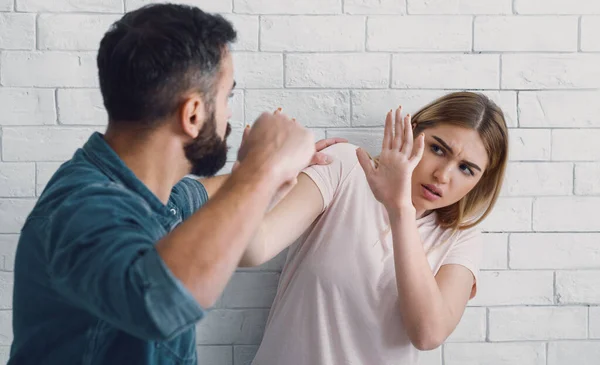 Son mari bat sa femme à la maison. L'homme en colère lève son poing contre la femme effrayée — Photo