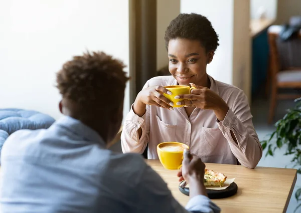 彼のガールフレンドとハンサムな黒人男性芳香族コーヒーを楽しんで、街のカフェでフレンドリーな会話をしています — ストック写真