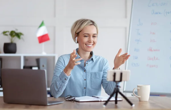 Estudiar lenguas extranjeras de forma remota. Alegre tutor femenino enseñando italiano en la web, dando lecciones en línea en el teléfono inteligente —  Fotos de Stock