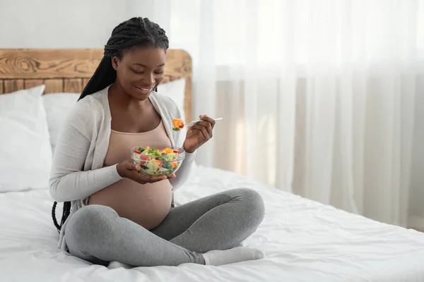 Těhotná výživa ženy. Šťastné černošky čeká dáma Eacting zeleninový salát v posteli — Stock fotografie