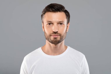 Gri arka planda yakışıklı sakallı adamın portresi.