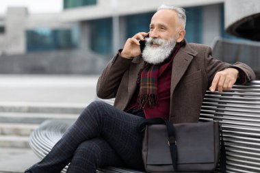 Son sınıf öğrencisi telefonda konuşuyor, bankta oturuyor.