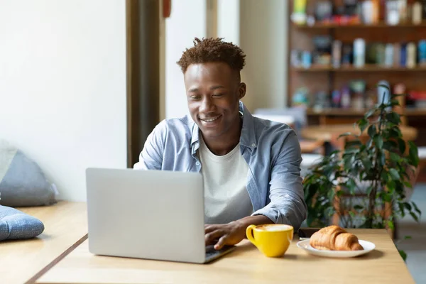 Funky zwarte man met behulp van laptop computer voor online werk of studies in gezellige stad cafe — Stockfoto