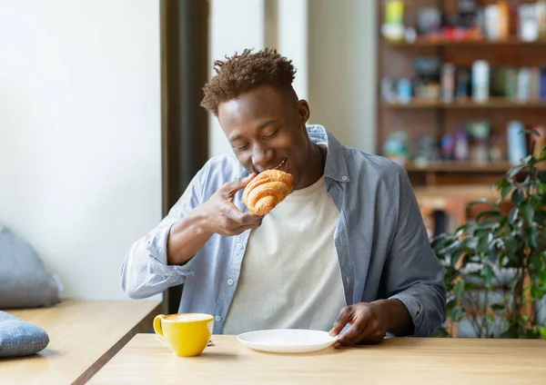 Cool Funky afro-americano cara comer croissant com café, tomando café da manhã no café da cidade — Fotografia de Stock