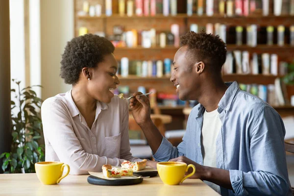 魅力的な若いです黒男給餌彼のガールフレンドとケーキ,ロマンチックなバレンタインディナーで居心地の良いカフェ — ストック写真