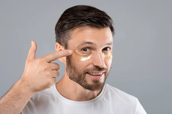 Bell'uomo che applica macchie sugli occhi sul suo viso — Foto Stock