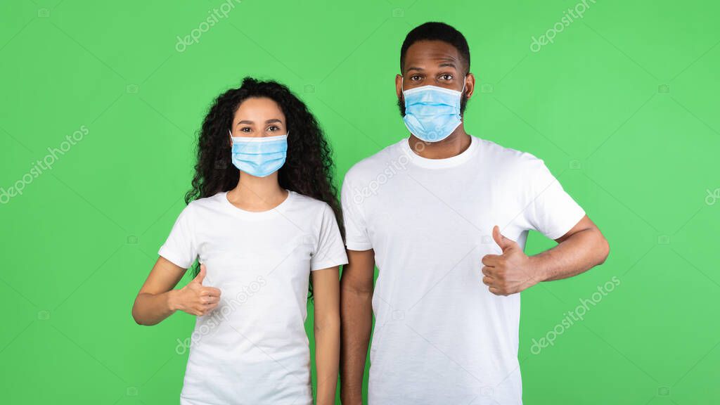 Diverse Couple Wearing Face Masks Gesturing Like, Green Background, Panorama