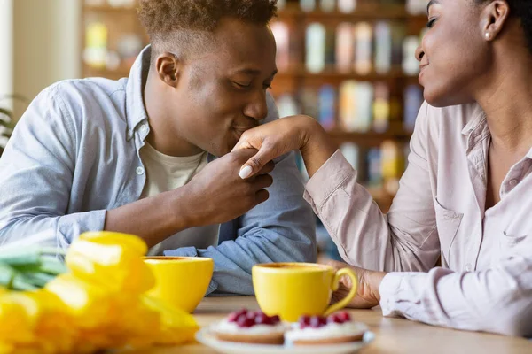 Romántico joven besando a sus amadas mujeres mano en la cena festiva de San Valentín en el acogedor café —  Fotos de Stock