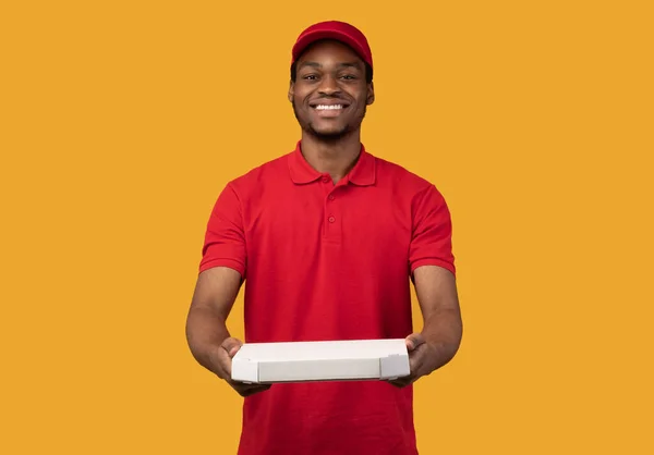 Svart leverans man som håller pizza box, ger den till kameran — Stockfoto